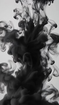Black ink cloud bursting and dissolving into clear water on light background