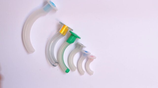 Set of colorful oropharyngeal airway tubes in different sizes arranged on white background, medical equipment for airway management
