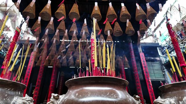 Smoke rising from traditional incense sticks in an ornate burner surrounded by hanging spiral incense coils in a historic Chinese temple, Cholon, District 5, Ho Chi Minh City, Vietnam