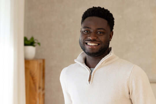 African American man standing at home smiling at camera in beige zip sweater showing zipper pull