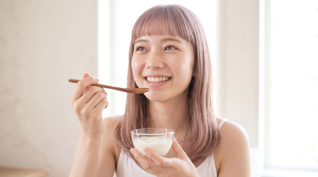 自然光に包まれた白い部屋で微笑む若い日本人女性
