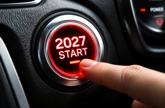 Finger pressing glowing red car engine start stop ignition button with text 2027 start representing New Year beginning and motivation concept stock photo