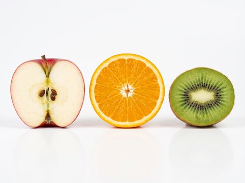 Halved apple orange and kiwi fruit arranged in a row showing fresh pulp