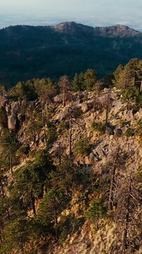 Stunning vertical video aerially captures the rugged slopes, rocky outcrops, and dense forest of Nevado de Colima under warm natural light, perfect for mobile reels and stories.