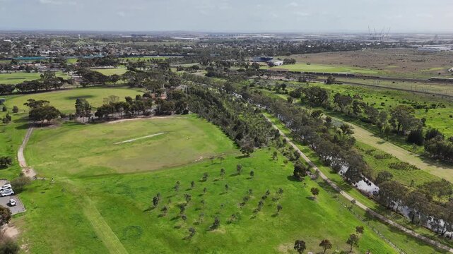 Laverton Creek flowing along grassy parklands, sports fields, and walking trails adjacent to residential neighborhoods and open reserves in Altona Meadows, Victoria, Melbourne, Australia