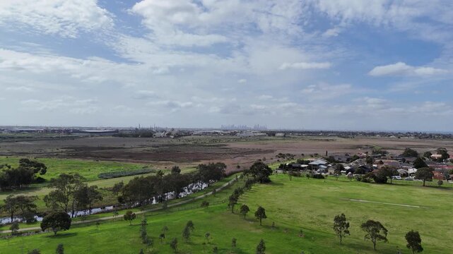 Laverton Creek and surrounding open native grasslands adjacent to suburban housing in Altona Meadows, with the distant CBD skyline. Melbourne, Victoria, Australia