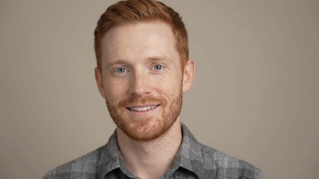 Smiling man with red hair posing in a neutral studio background