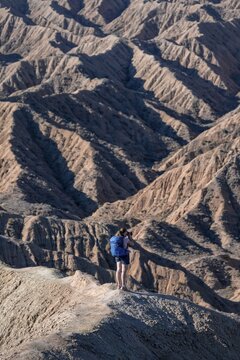 Hiker walking along a canyon, eroded hilly landscape, Badlands, Valley of the Forgotten Rivers, near Bokonbayevo, Yssykk&ouml;l, Kyrgyzstan
