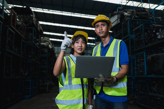 Warehouse workers using laptop for inventory management in industrial storage