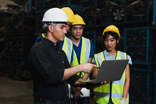 Industrial workers and supervisor using laptops for meeting in warehouse storage facility
