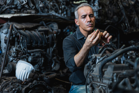 Professional mechanic inspecting and repairing car engine in automotive spare parts warehouse