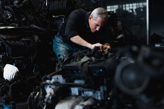 Professional mechanic inspecting and repairing car engine in automotive spare parts warehouse