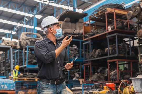 rofessional supervisor in mask using radio and tablet in automotive spare parts warehouse