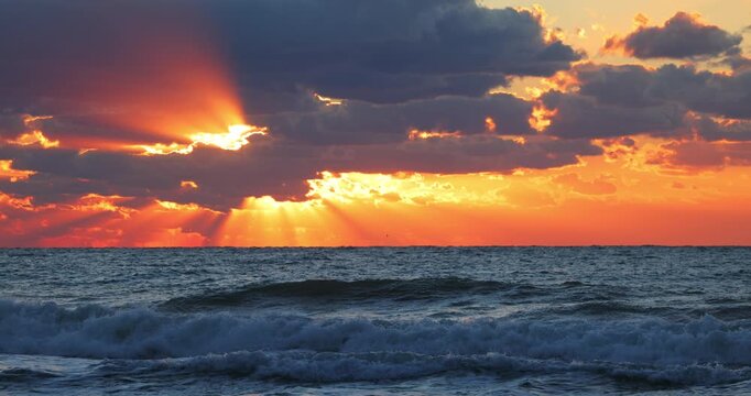 summer sunrise over sea horizon and beach with dramatic cloudscape and sunlight