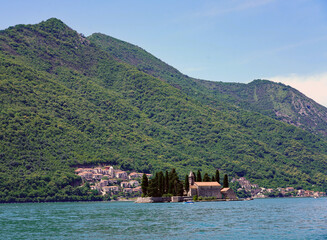 The historic Benedictine monastery on the island of Saint George stands surrounded by cypress trees in the Bay of Kotor beneath steep, forested mountains near Perast, Montenegro © Gregory