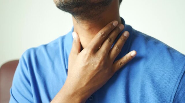 A man's hand checking his neck for a pulse and signs of discomfort, focusing on the throat area, a health and medical concept