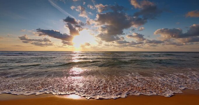 Ocean waves rolling on the sea sand toward sandy beach at sunrise