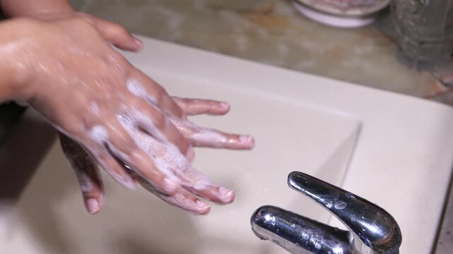Close up video clip of a person washing hands with soap in a sink showing proper hand hygiene to prevent the spread of germs and viruses