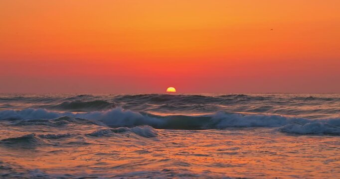 Scenic Sunrise Over Ocean Waves Crashing Toward the Sea Shore and beach With Vibrant Orange Sky seascape video