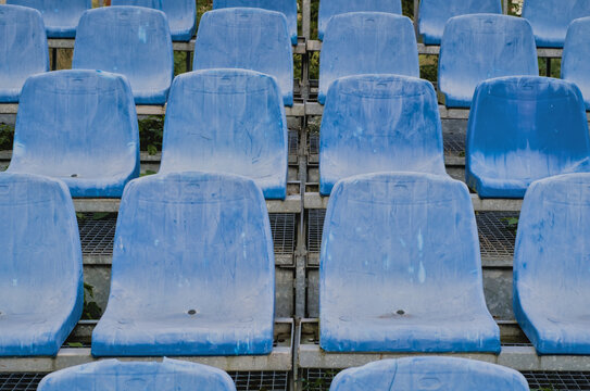 Old dirty plastic stadium seats in multiple rows