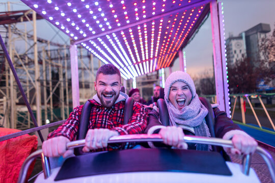 Happy couple screaming riding roller coaster fun