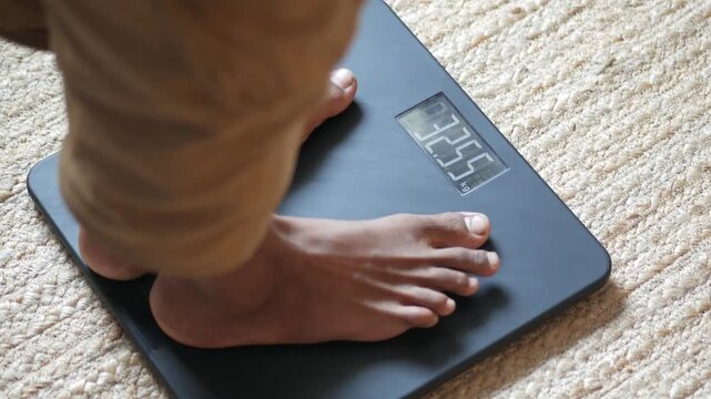 A close up cinematic view of person standing on digital weight scale, checking body mass with care and precision