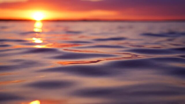 Close up of ocean water waves reflecting vibrant orange sunset