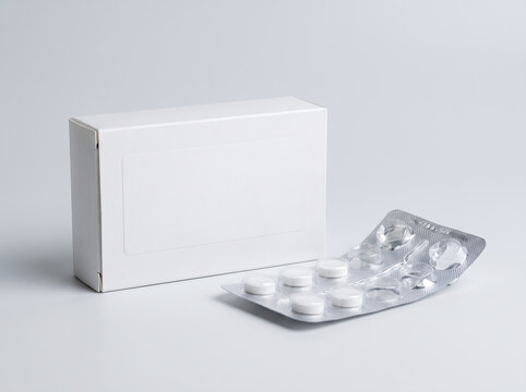 Blank white medicine box with a blister pack of white round tablets on a neutral background transparent background
