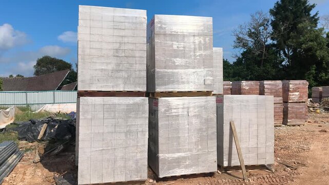 Stacked AAC block pallets sit on a construction site. These lightweight concrete blocks accelerate wall building and streamline workflow.