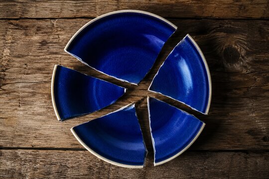 Broken blue ceramic plate on rustic wooden table