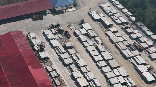 Aerial perspective showing industrial storage yard with many concrete blocks and heavy vehicles