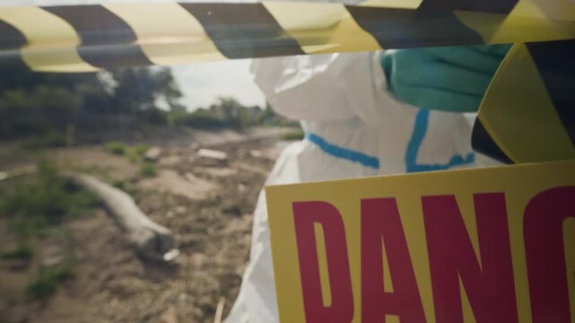 Environmental inspector cordoning off polluted zone with yellow barrier tape near toxic danger sign. Perfect for ecological disaster documentaries, news reports, and hazard awareness videos