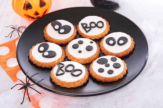Halloween Decorated Cookies with Boo Text and Ghost Eyes Served on Black Plate