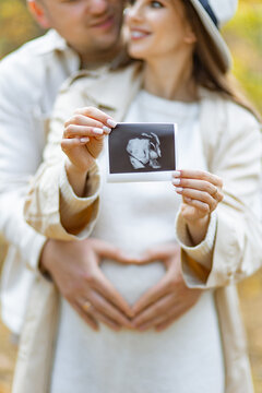 A couple lovingly holds an ultrasound image, celebrating their upcoming parenthood