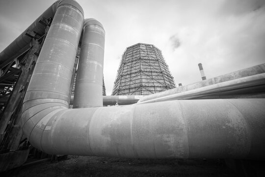 Industrial heating pipelines and giant cooling tower of power plant monochrome background with copy space