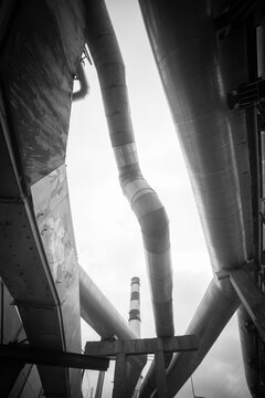 Vertical industrial pipelines and factory chimney monochrome abstract background with copy space