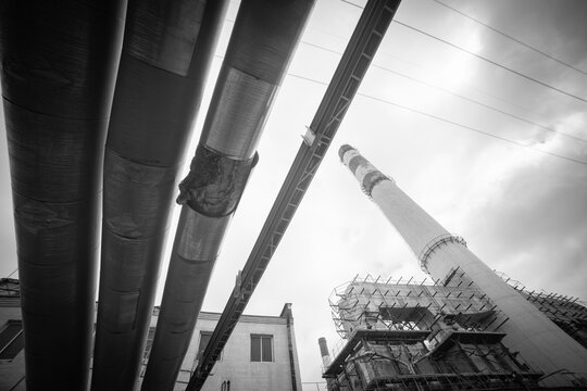 Damaged industrial heating pipeline and factory smokestack monochrome background with copy space