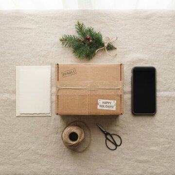 Festive gift package with evergreen branch and holiday twine on a linen background