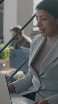 Young Middle Eastern businesswoman making online video call with smartphone on stairs in coworking office. Virtual meeting and distance communication concept.