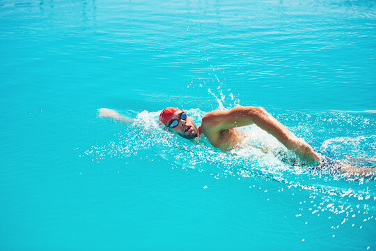 Fitness, man and swimming in pool for exercise, workout and aquatic practice for body wellness. Male person, swimmer and training for water sports, freestyle stroke and healthy lifestyle in summer