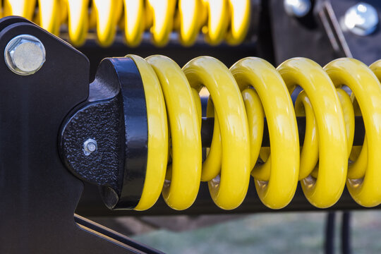 Steel yellow spring as part of heavy agricultural, industrial machine. Technology
