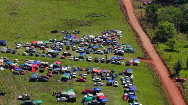 Drone video captures vibrant WRC Rally 2026 campsite in Nueva Alborada, Paraguay, with colorful tents, parked cars, grassy fields, red dirt road, and festive outdoor crowd atmosphere.