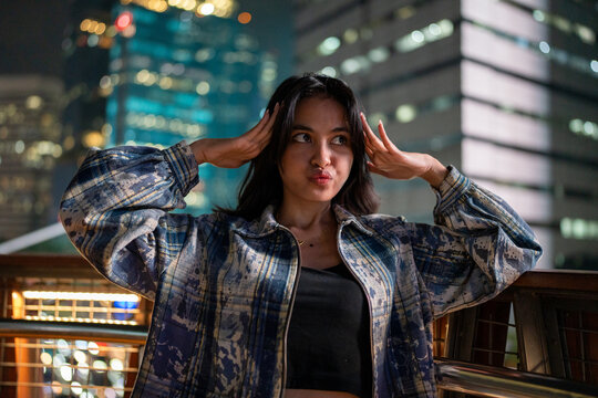 Young woman making a playful expression at night in city