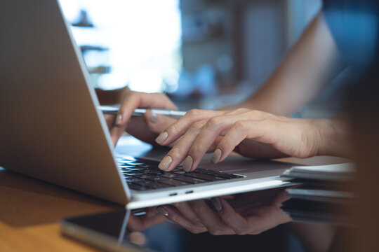 Close up of woman hands typing, browsing the internet, working on laptop with digital tablet on table at cafe or office workspace, remote work, online business concept