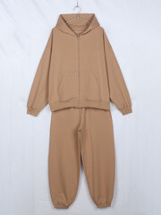 Beige oversized tracksuit with zip hoodie and sweatpants on hanger isolated on white background © Radik