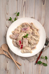 Traditional sweet cherry dumplings vareniki pierogi garnished with mint on plate on rustic light...
