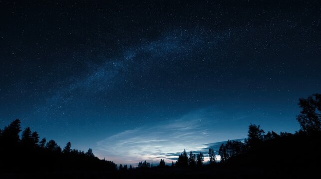 Milky way galaxy diagonally crossing night sky between dark pine forest silhouettes with faint cloud glow near horizon