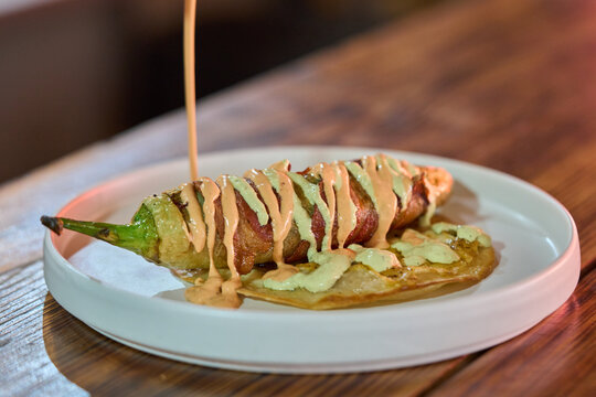 Chile Relleno Envuelto En Tocino Sobre Tortilla De Queso Con Aderezo Estilo Mariscos