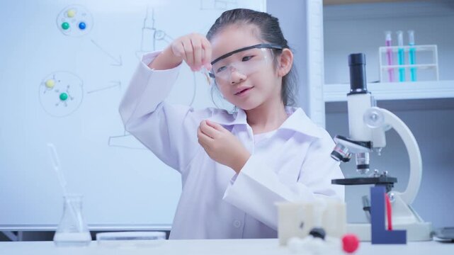 Asian girl scientist examining test tube sample in laboratory for stem education and school learning concept