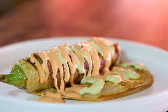 Chile Relleno Envuelto En Tocino Sobre Tortilla De Queso Derretido Con Relleno De Mariscos